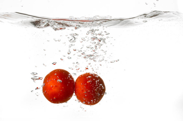 Red tomatoes falling into water - Foto, imagen
