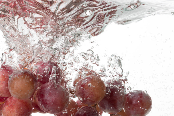 Uvas caindo na água perto no fundo branco
 - Foto, Imagem
