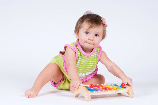 Girl with excitement playing on a xylophone isolated on white - Photo, Image