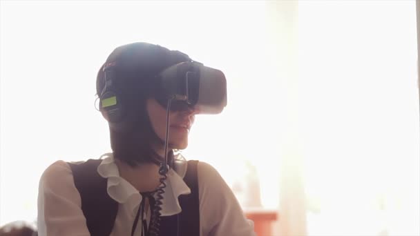 Young brunette woman playing game using VR-helmet for smart phones. Augmented reality device allows to deep into virtual space - Footage, Video