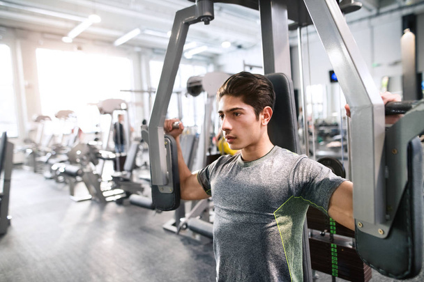 Hispanic man in gym sitting on bench, working out with weights - Photo, Image