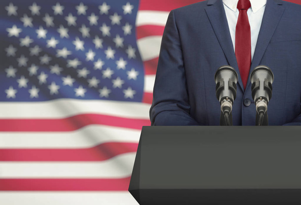 Uomo d'affari o politico che fa un discorso da dietro un pulpito con bandiera nazionale sullo sfondo - Stati Uniti - Foto, immagini