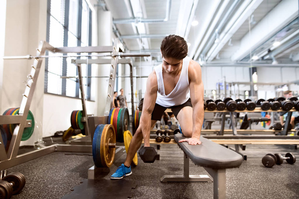 Hispanic man in gym on bench, working out with weights - Zdjęcie, obraz