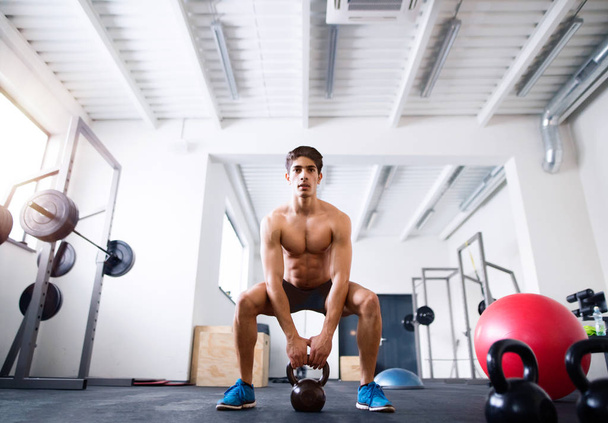 Young fit hispanic man in gym doing kettlebell swings - Foto, afbeelding