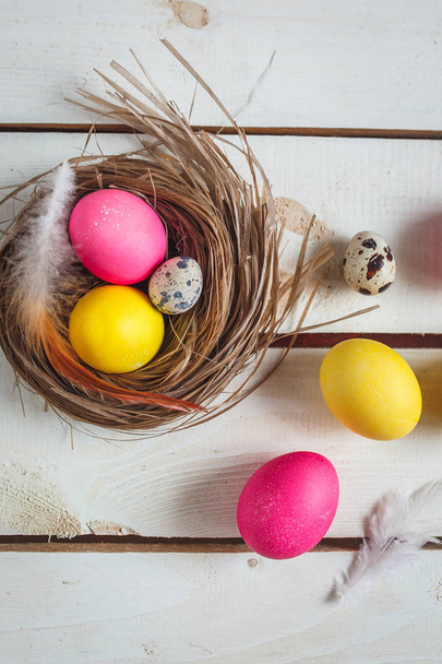 Easter background with yellow and pink eggs . Top view with copy space . Easter eggs in nest on rustic wooden planks - Foto, imagen