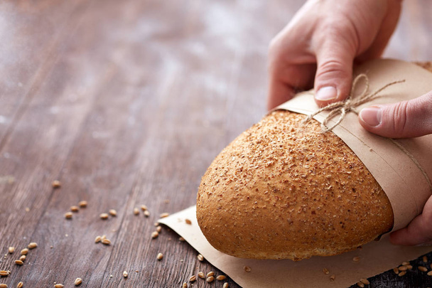 Baker hands with fresh bread on wood table - Fotó, kép