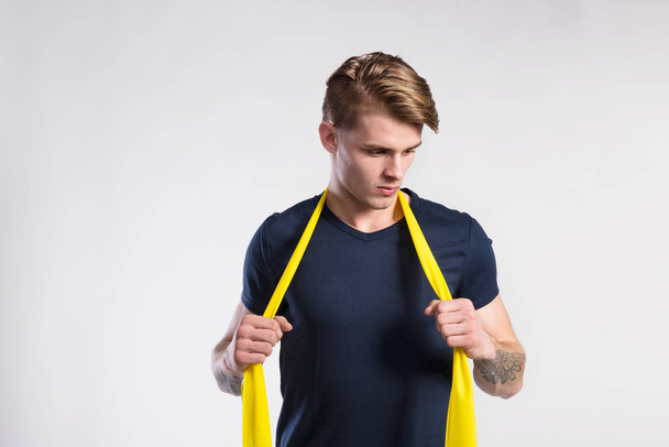 Fitness man working out with resistance bands, studio shot. - Foto, afbeelding