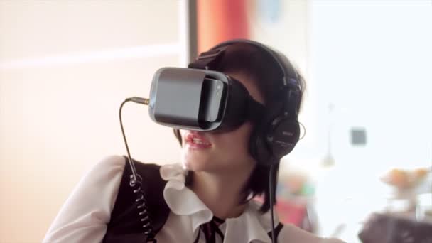 Mujer morena joven jugando a juegos con casco VR para teléfonos inteligentes. Dispositivo de realidad aumentada permite profundizar en el espacio virtual
 - Imágenes, Vídeo