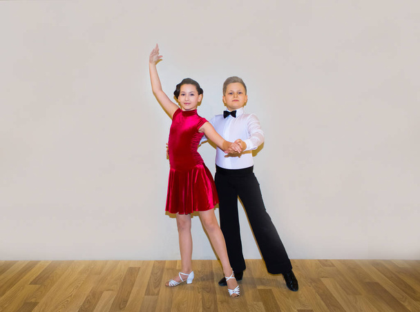 Мальчик и девочка позируют в танцевальной студии на сером. Концепция бальных танцев
 - Фото, изображение