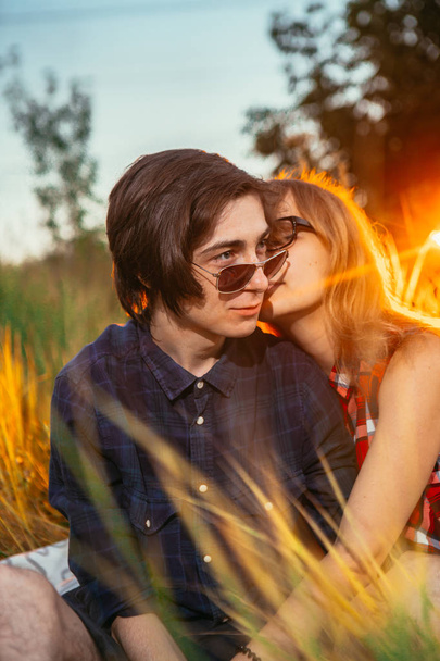 guy and the girl sitting in the grass on a sunset background - 写真・画像