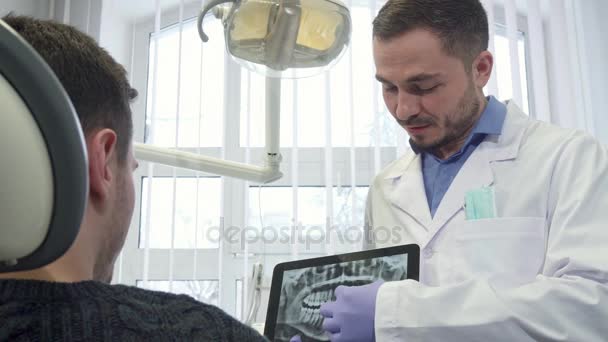 Οδοντίατρος αρσενικό πελάτη ακτινογραφία δείχνει στο του tablet - Πλάνα, βίντεο