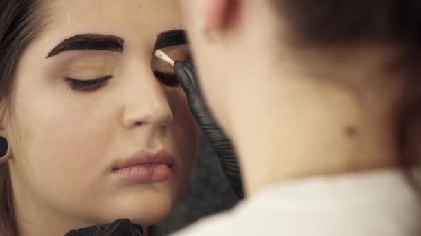 Makeup artist fixing the shape of painted eyebrows closeup - Felvétel, videó