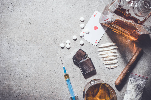Overhead shot of hard drugs and alcohol on gray stone background - 写真・画像