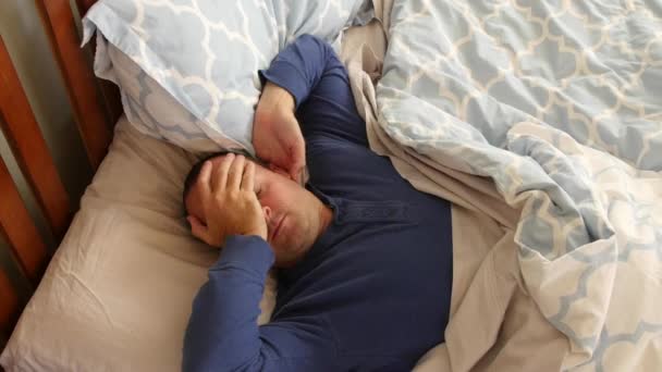 Un hombre cansado se despierta por la mañana en la cama
 - Imágenes, Vídeo
