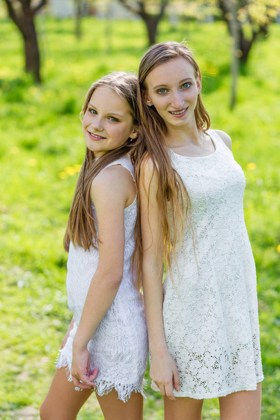 Two beautiful young girls in white dresses in summer  - Foto, Imagen