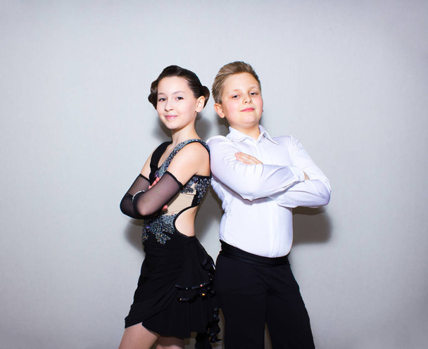De jongen of het meisje met mannelijke coach of leraar poseren op dansstudio op grijs. De ballroom dancing school en onderwijs concept - Foto, afbeelding
