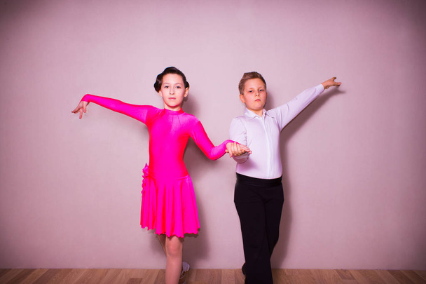 El niño y la niña posando en el estudio de baile en gris. El concepto de baile de salón
 - Foto, imagen