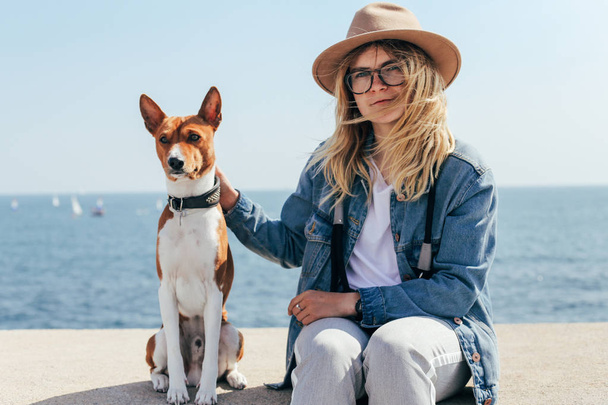 Girl and dog sit on seaside - Photo, Image