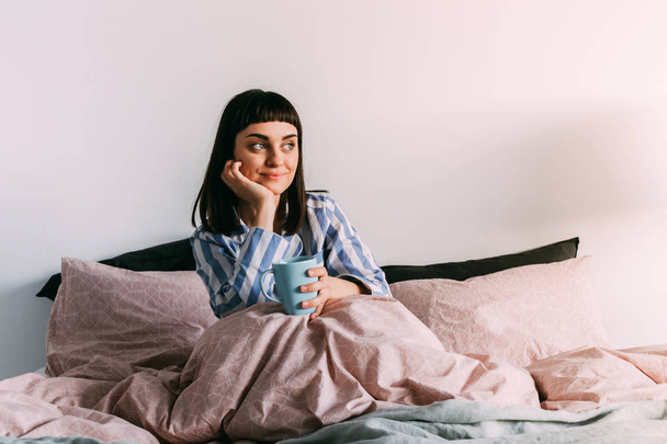 Хипстерская девушка, лежащая в постели с кофе
 - Фото, изображение