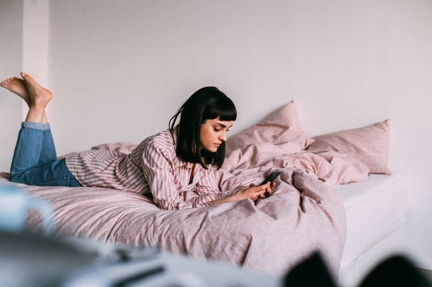 Hipster meisje loungen in bed met koffie - Foto, afbeelding