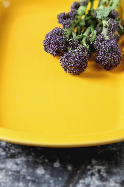Fresh purple broccoli on a yellow plate. Dark background. - Foto, Imagem