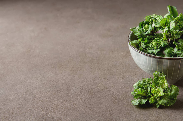 Fresh kale cabbage in a ceramic bowl. Dark gray background. - Photo, image