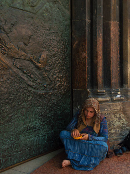 Φιλανθρωπία, νεαρό κορίτσι επαιτεία έξω από μια εκκλησία - Φωτογραφία, εικόνα