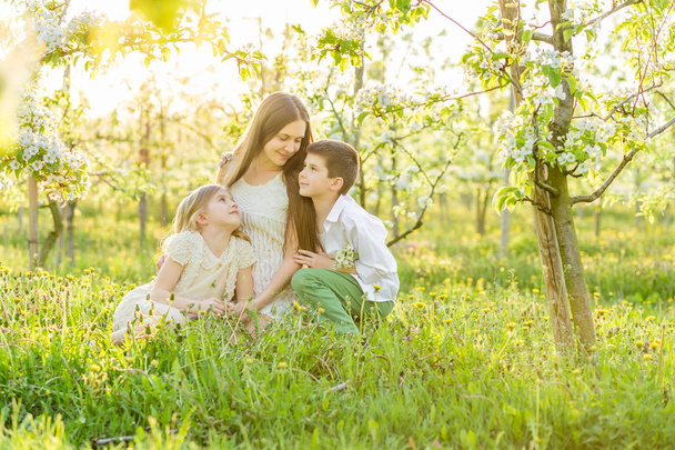 Gyönyörű, fiatal család egy virágzó tavaszi kert.  - Fotó, kép