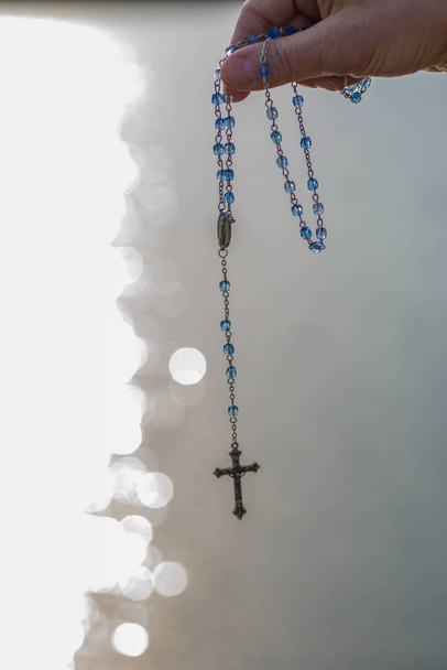 rosary in sunlight along lake reflection - Photo, Image