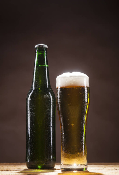 Beer bottle and mug on brown background - Valokuva, kuva