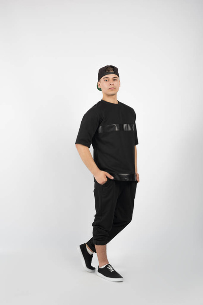 Svalnatý mladík na sobě černé oblečení a tenisky - Fotografie, Obrázek