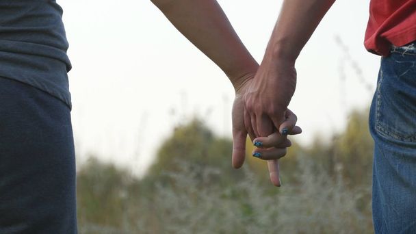 Young couple joining hands outdoor. Man and woman taking arms on nature background. Male and female hands comforting and stroking each other. Symbol of love and devotion. Romantic outside. Close up - Fotó, kép