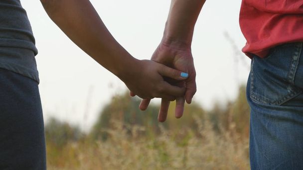 Young couple joining hands outdoor. Man and woman taking arms on nature background. Male and female hands comforting and stroking each other. Symbol of love and devotion. Romantic outside. Close up - Fotó, kép