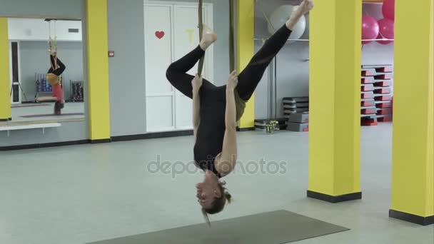 De kapitein van yoga doen een omgekeerde pose opknoping op een hangmat tape voor aerial yoga - Video