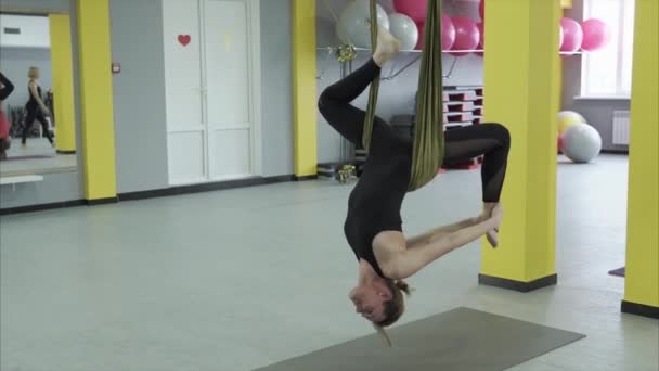 De kapitein van yoga doen een omgekeerde pose opknoping op een hangmat tape voor aerial yoga - Video