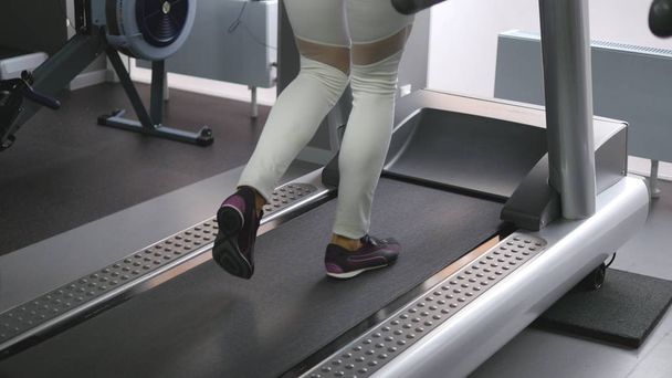 Γυναικεία πόδια που περπατούν και τρέχουν με διάδρομο στο γυμναστήριο. Νέα γυναίκα άσκηση κατά τη διάρκεια της καρδιαγγειακής προπόνησης. Πόδια των κοριτσιών σε αθλητικά παπούτσια εκπαίδευση σε εσωτερικούς χώρους στο Sport Club. Άνθρωποι που τρέχουν. Κοντινό - Φωτογραφία, εικόνα