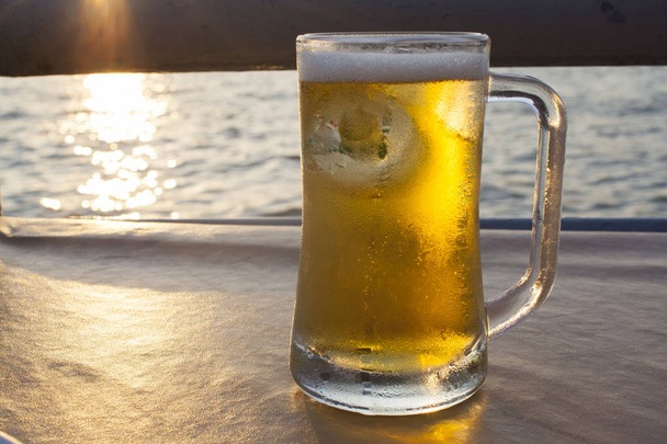 tarja sört inni, este folyó mellett  - Fotó, kép