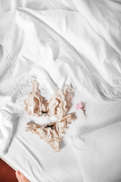 schöne Unterwäsche aus Seide liegt auf einem weißen Bett - Foto, Bild