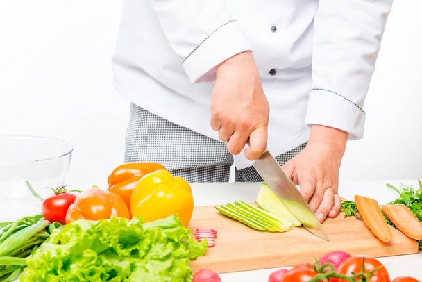 Chef corta salada, prepara legumes frescos no fundo branco
 - Foto, Imagem