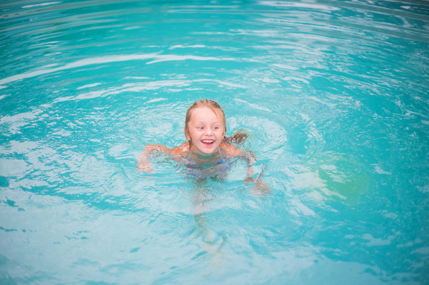 Portrait of cute happy little girl having fun in swimming pool.  Kids sport on family summer vacation. Active healthy holida - Valokuva, kuva