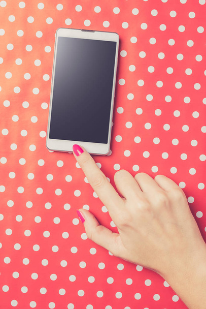 Woman using white smart phone over red dotted background - Foto, immagini