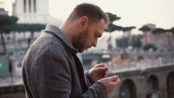 El hombre con estilo se encuentra en el centro de Roma, Italia. El hombre guapo utiliza el teléfono inteligente, navegar por Internet
. - Metraje, vídeo