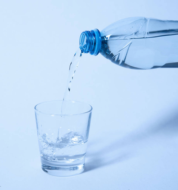 Víz ömlött a cumisüvegről a pohárba - Fotó, kép