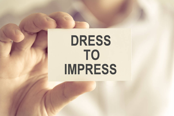 Empresario sosteniendo DRESS TO IMPRESS tarjeta de mensaje
 - Foto, Imagen