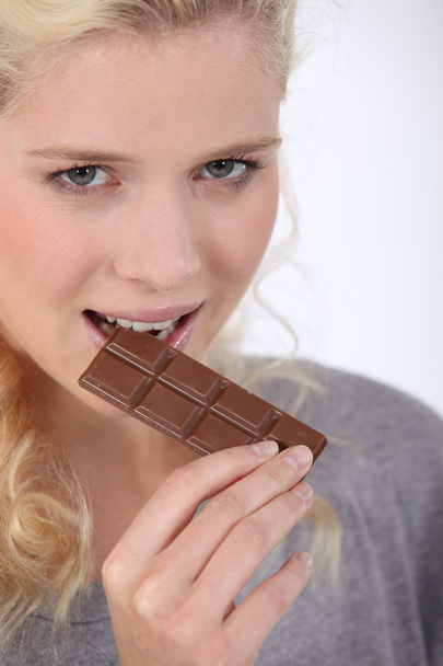 Woman biting a piece of chocolate - Foto, afbeelding