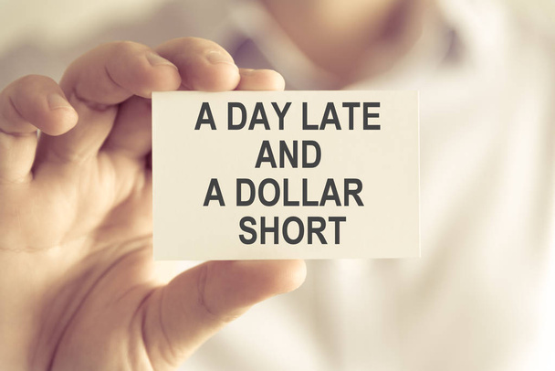 Zakenman holding A dag laat en een Dollar korte tekstkaartje - Foto, afbeelding