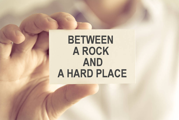 Geschäftsmann hält zwischen einem Felsen und einem harten Platz Nachrichtenkarte - Foto, Bild