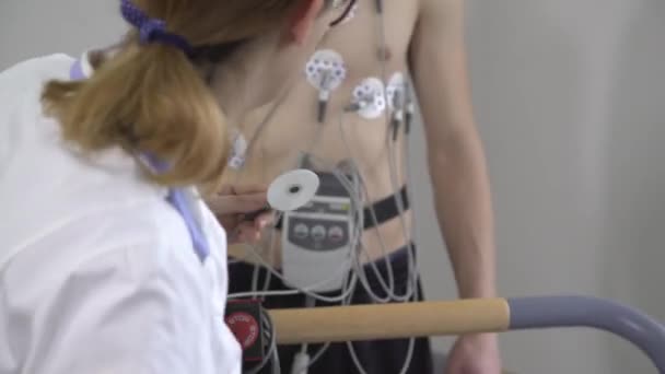 Female doctor monitors the progress of the a young man ECG - Materiał filmowy, wideo