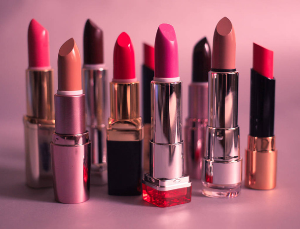 Joukko monivärisiä huulipunia vaaleanpunaisella taustalla
 - Valokuva, kuva