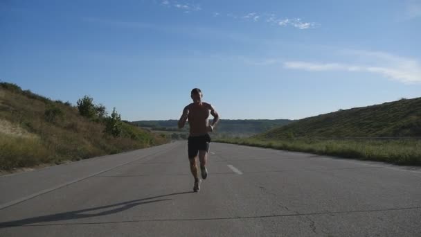 Sprinten runner man joggen op de snelweg. Mannelijke sport atleet training buiten in de zomer. Jonge sterke gespierde kerel uitoefenen op landelijke weg tijdens de training. Actieve en gezonde levensstijl buiten. Slow motion - Video